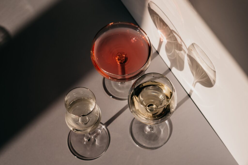 Three different wine glasses casting unique shadows in natural sunlight, showcasing elegance and variety.